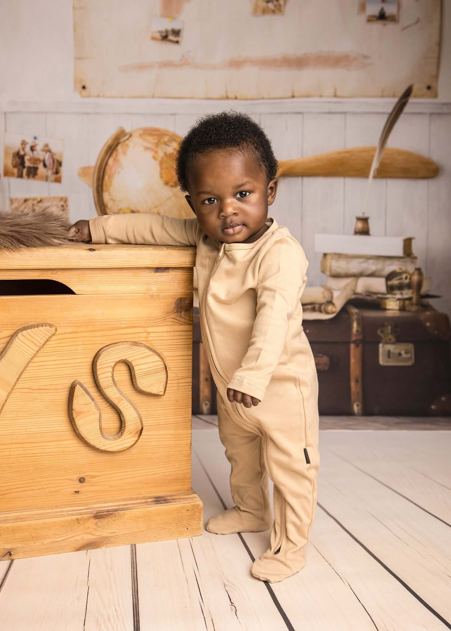Baby less than 12 months old, standing wearing a nueborn Khaki double zip sleepsuit