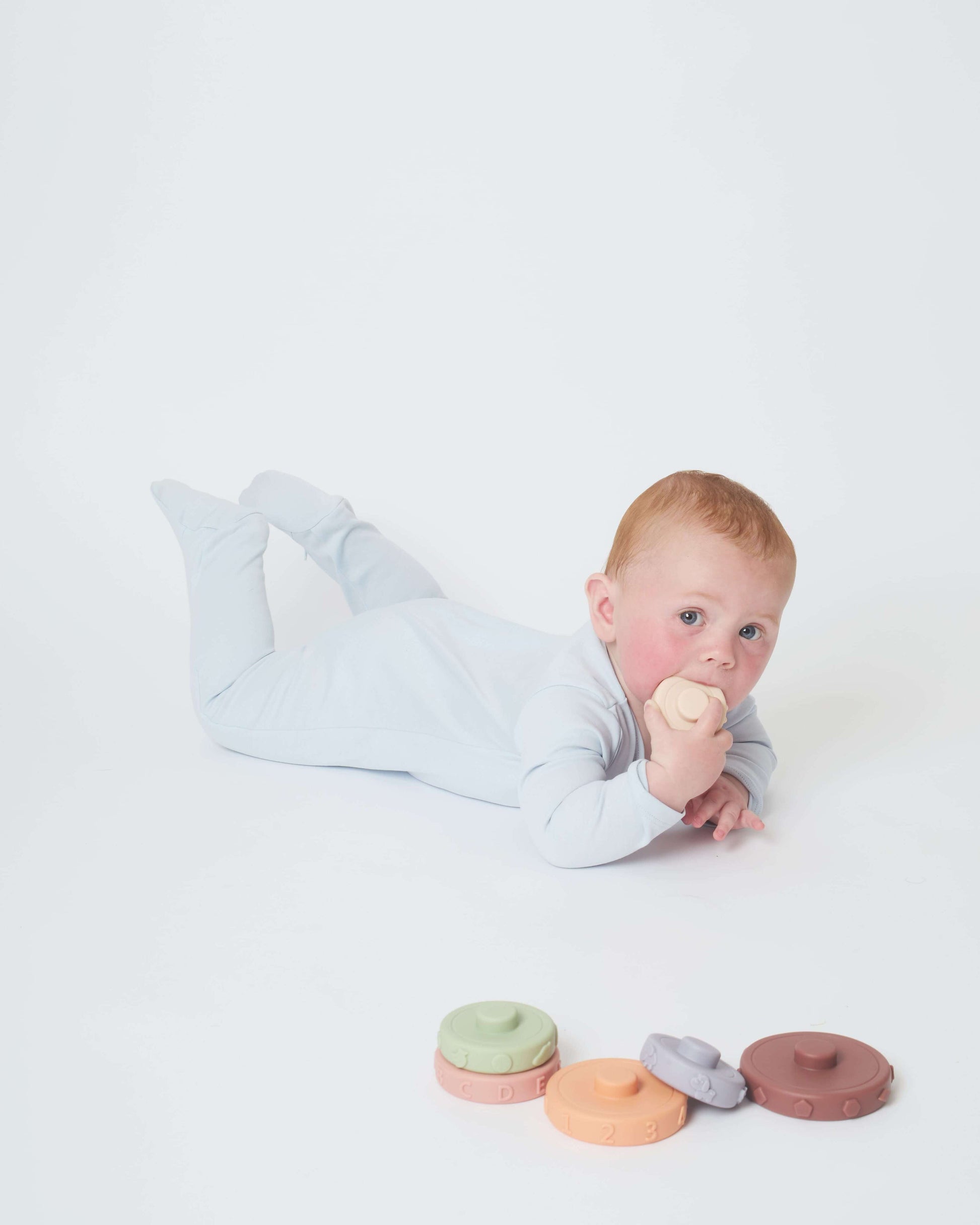 baby playing in his sky blue nueborn sleepsuit